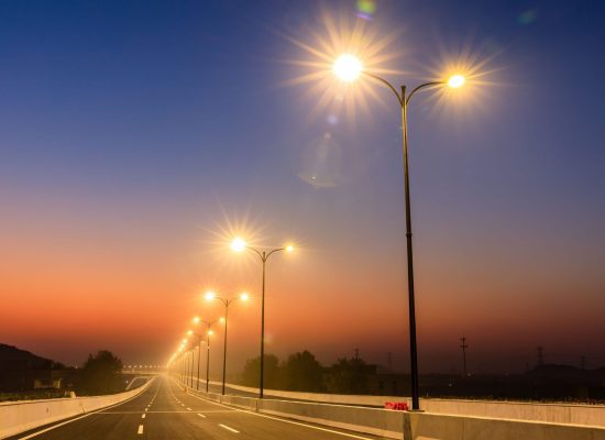 City road and bright street lights landscape at sunset